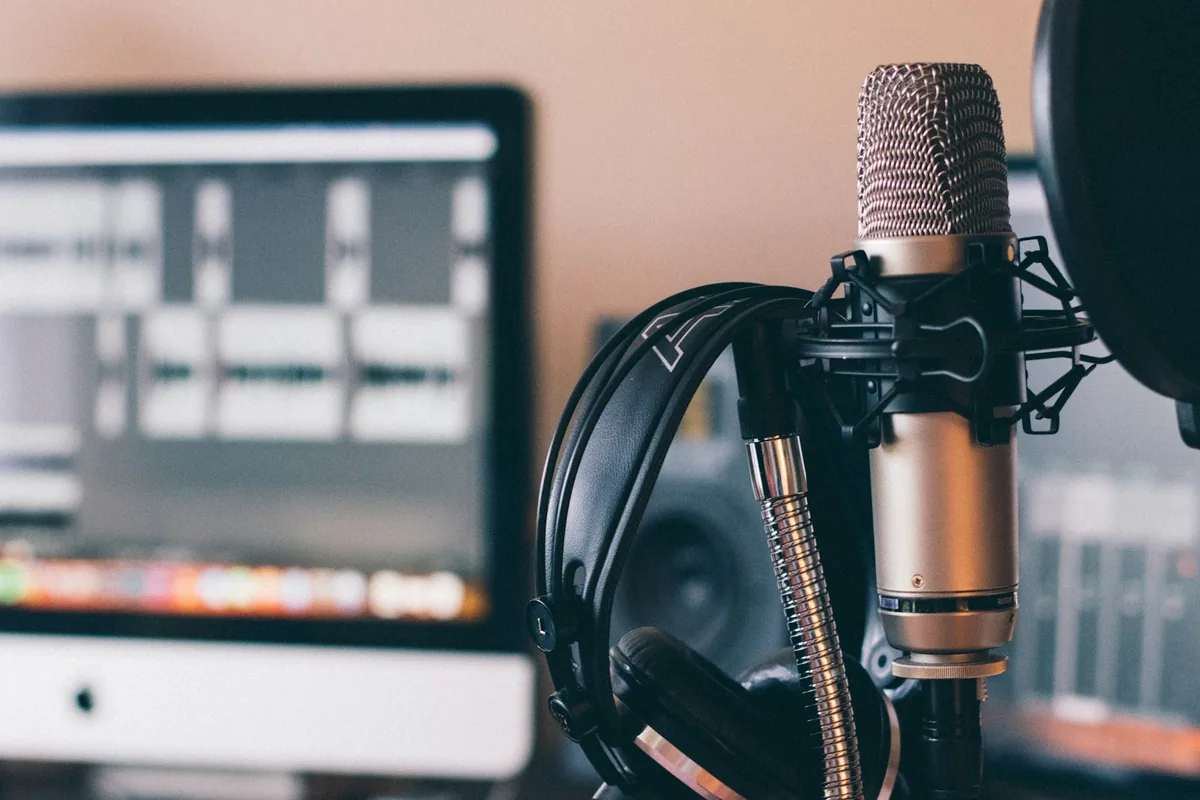 Studio condenser microphone with headphones and a screen in the background