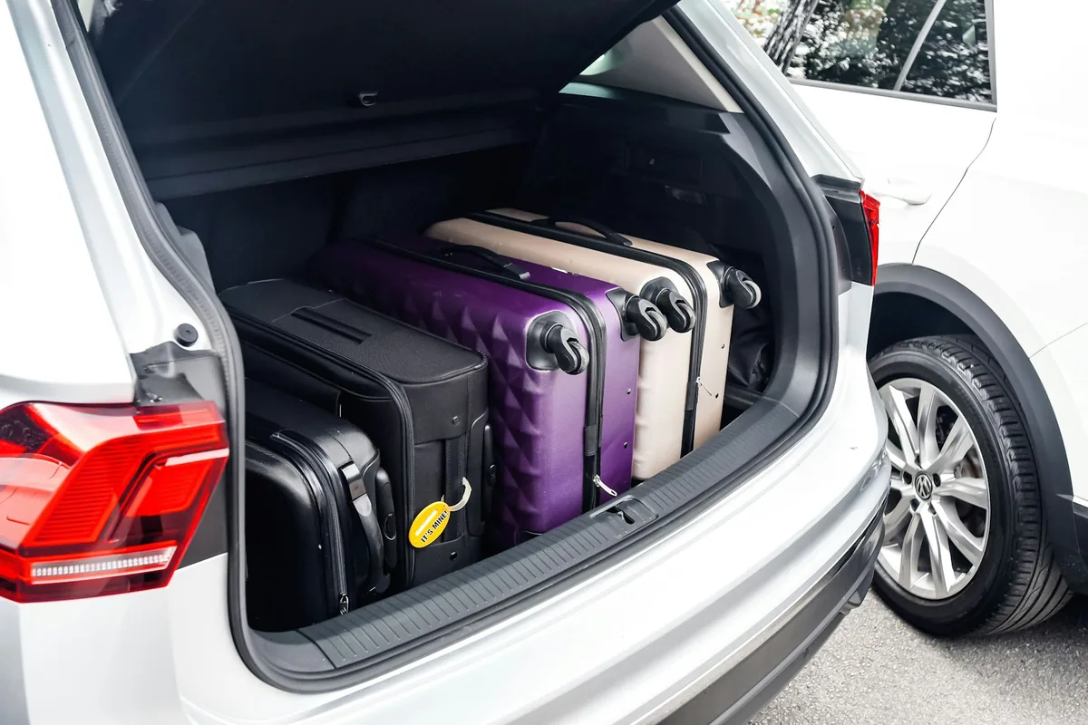 Koffers geladen in de open kofferbak van een witte auto