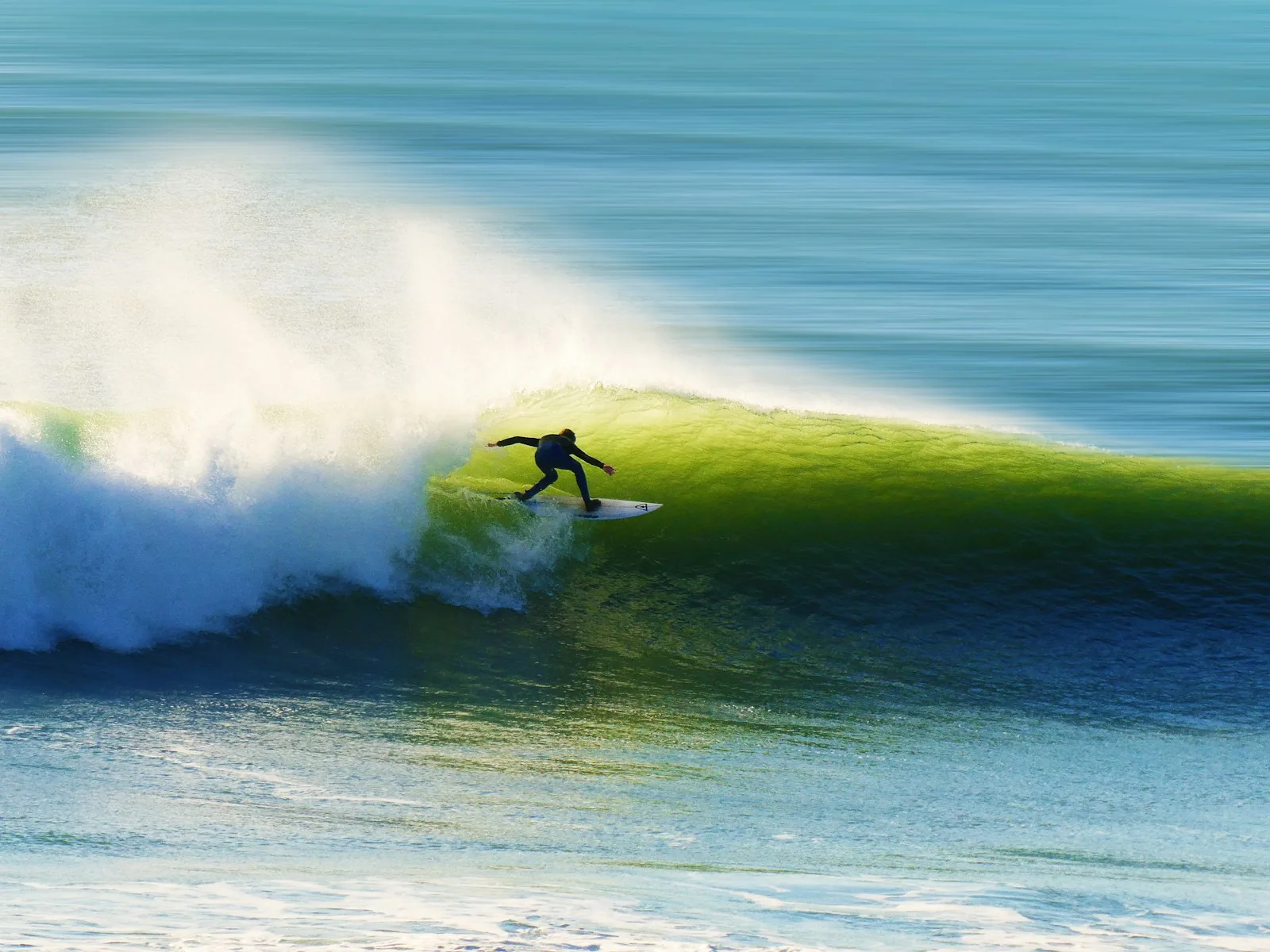 Un surfista deslizándose dentro de una ola verde