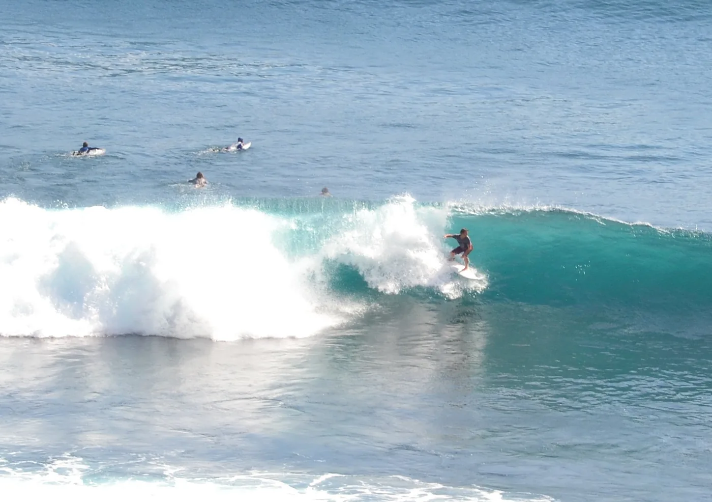 Surfers in the water behind a breaking wave at Uluwatu in Bali