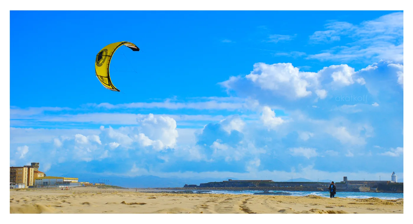Yellow kite in a blue sky above the beach and sea at Tarifa in winter