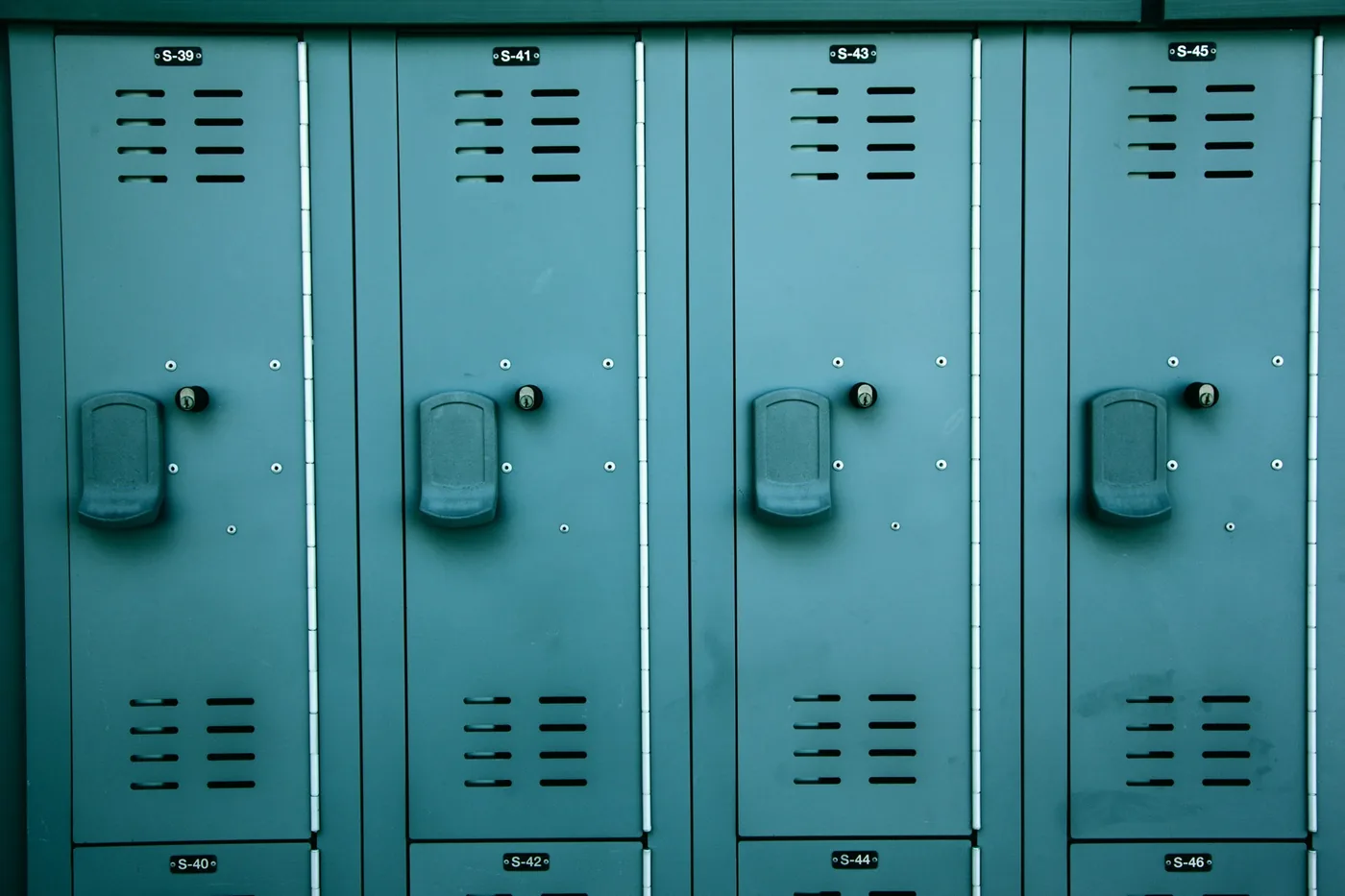 Row of teal metal lockers with numbered doors and keyholes
