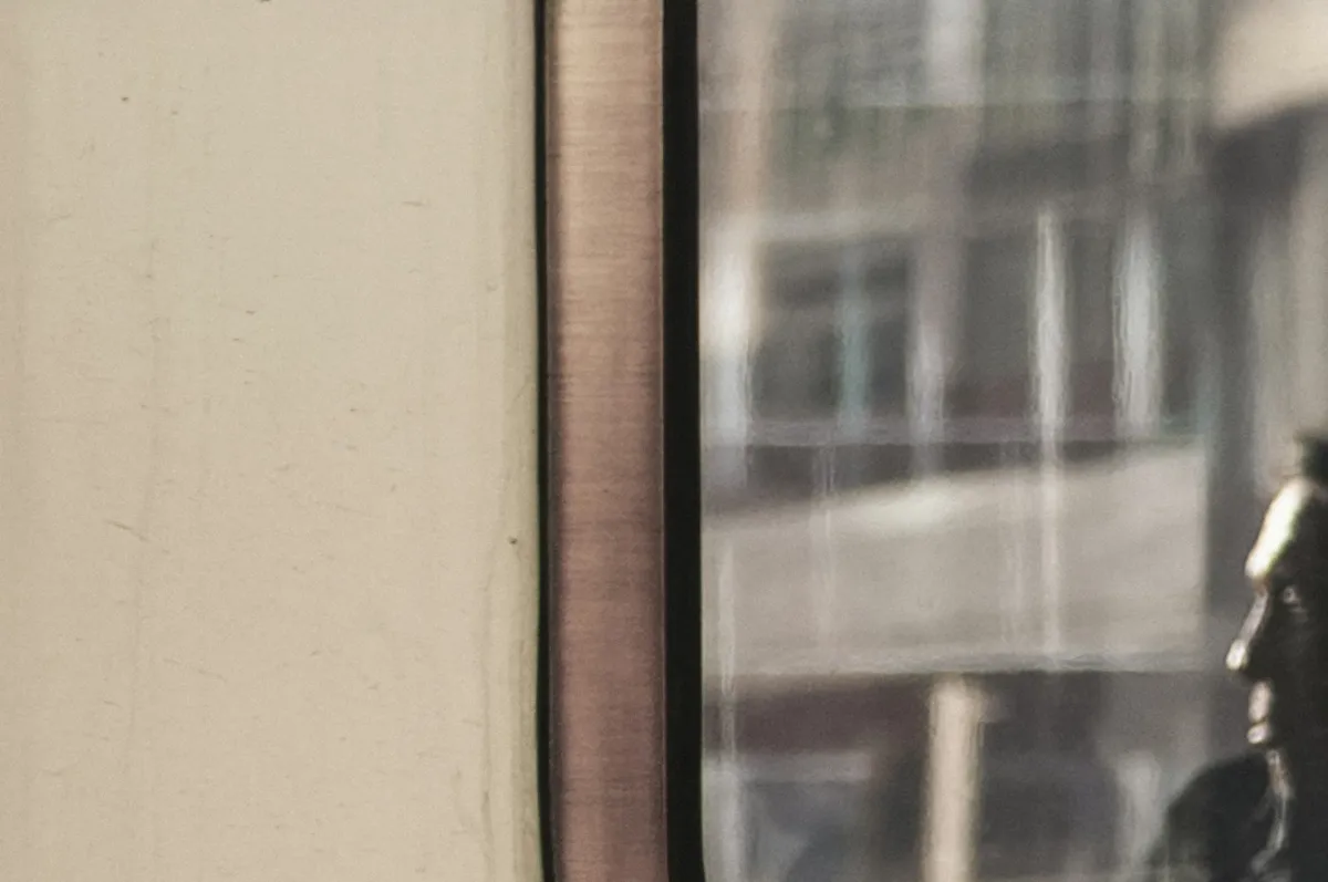 Train carriage window with a passenger reflected in the glass