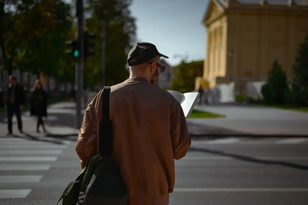 Traveler with a backpack seen from behind reading a map at a street crossing