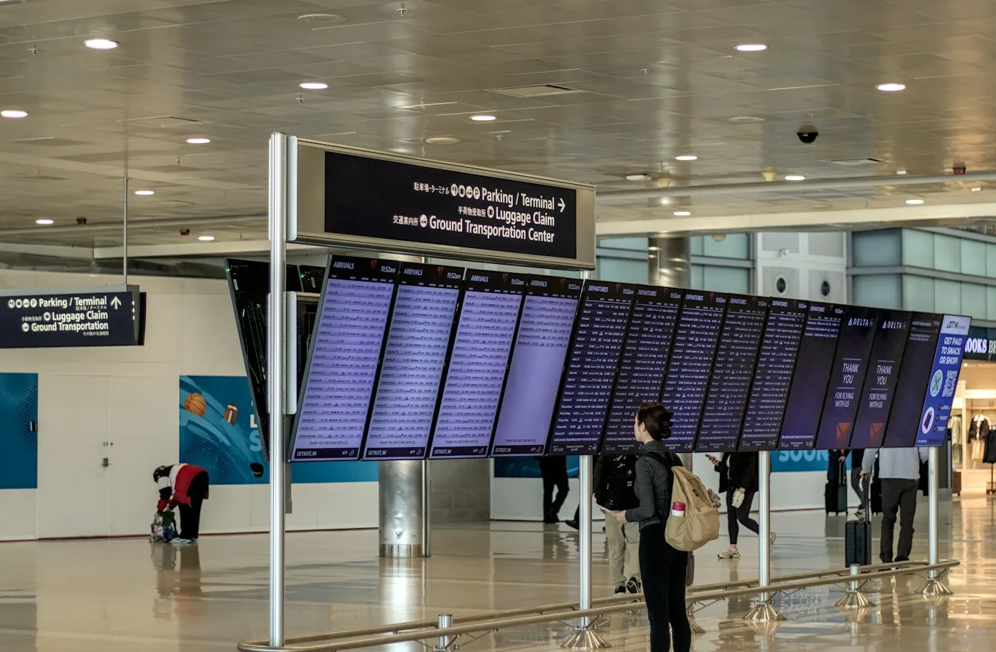 Traveler with a backpack looking at the departure board in an airport hall