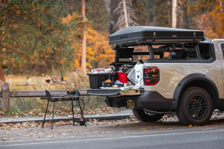 Pickup with an open tailgate, a camp table and cooking gear at an autumn roadside stop