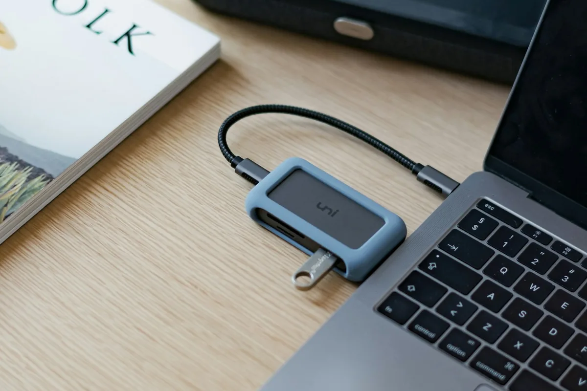Een zwarte USB-C-kabel aangesloten op een MacBook Pro op een houten bureau