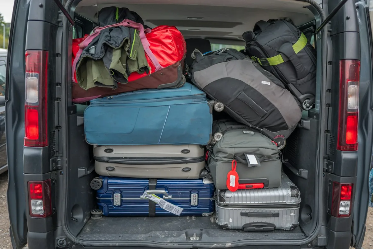 The open back of a van packed full with suitcases and bags for a road trip