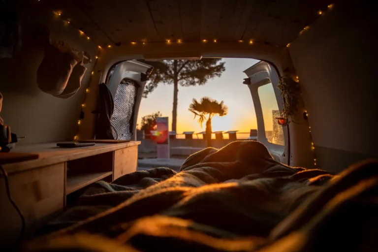 View out of a van back door at sunset with string lights along the ceiling