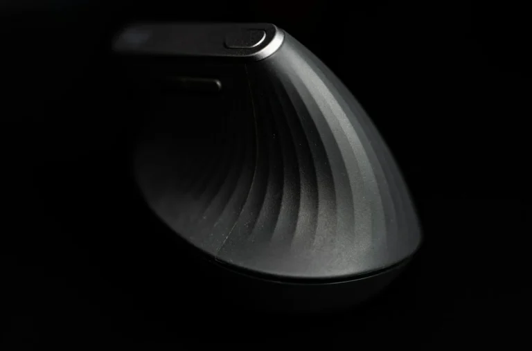 Black vertical ergonomic mouse with a ridged grip against a dark background