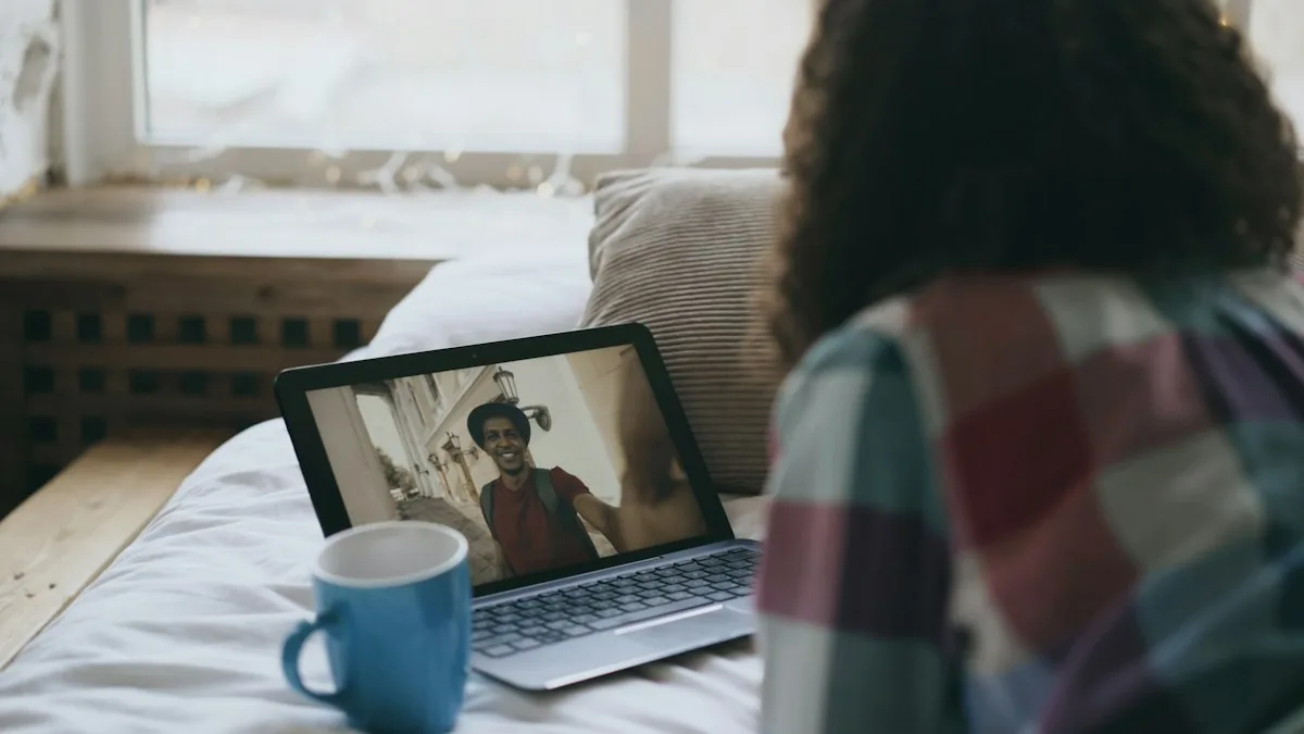 Woman on a bed in a video call on a laptop with a blue mug beside it