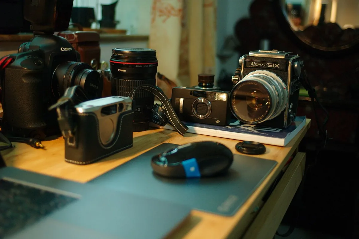 Vintage and modern cameras next to each other on a wooden desk