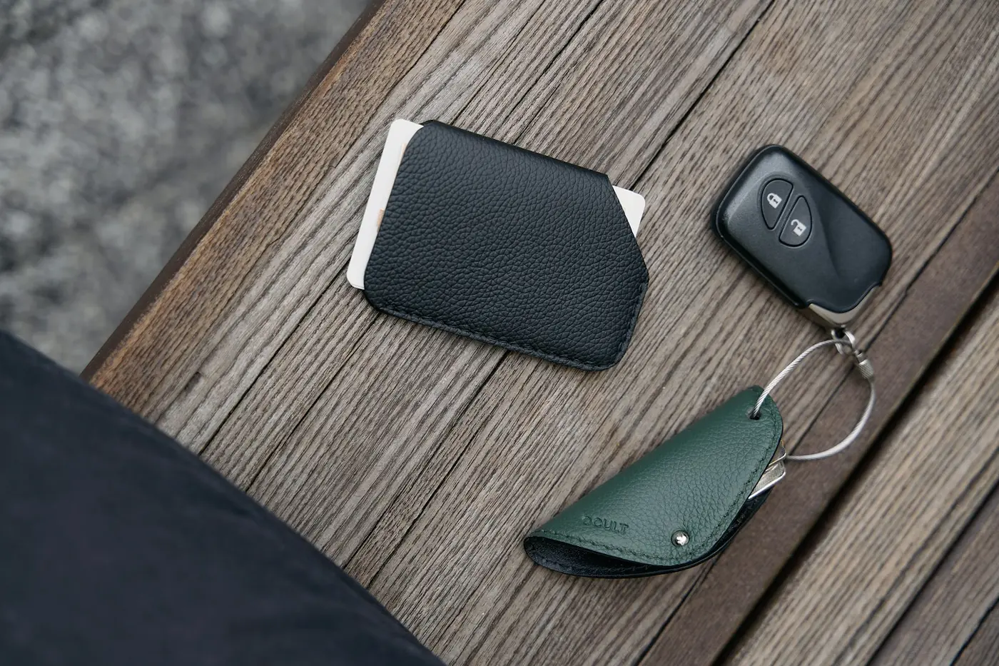 Phone, wallet and a car key with a key ring lying on a wooden table
