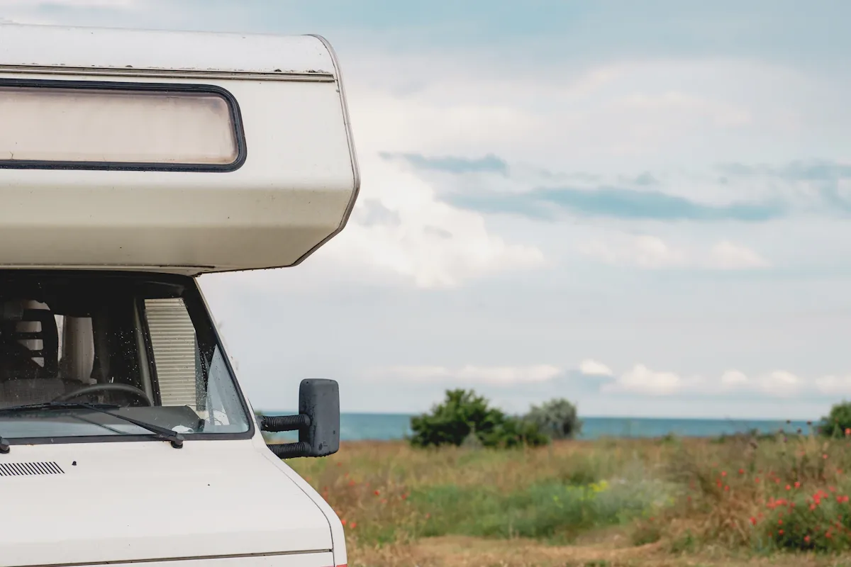 De voorkant van een witte motorhome geparkeerd op gras dicht bij de zee