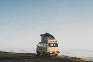 A camper van with a roof tent parked on a coastal road above the clouds