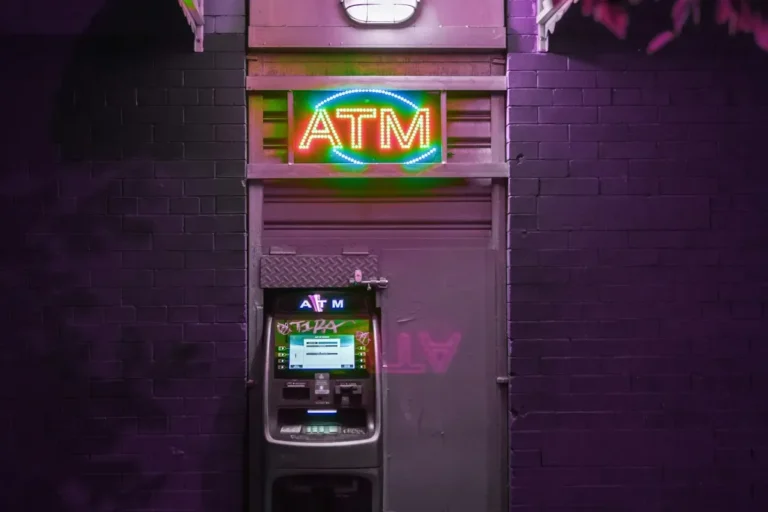 Lit ATM sign above a cash machine in a dark street at night