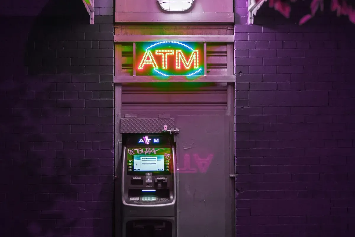 Lit ATM sign above a cash machine in a dark street at night