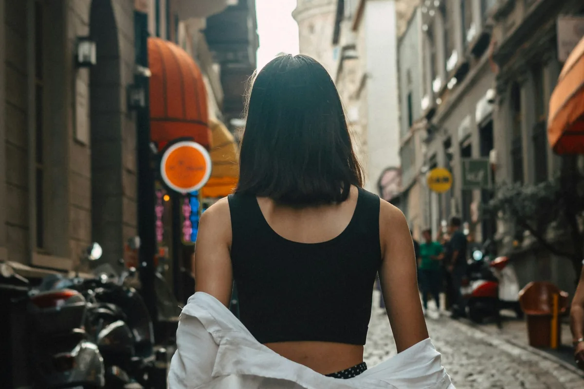 Een vrouw loopt over een kinderkopjesstraat in een oude binnenstad