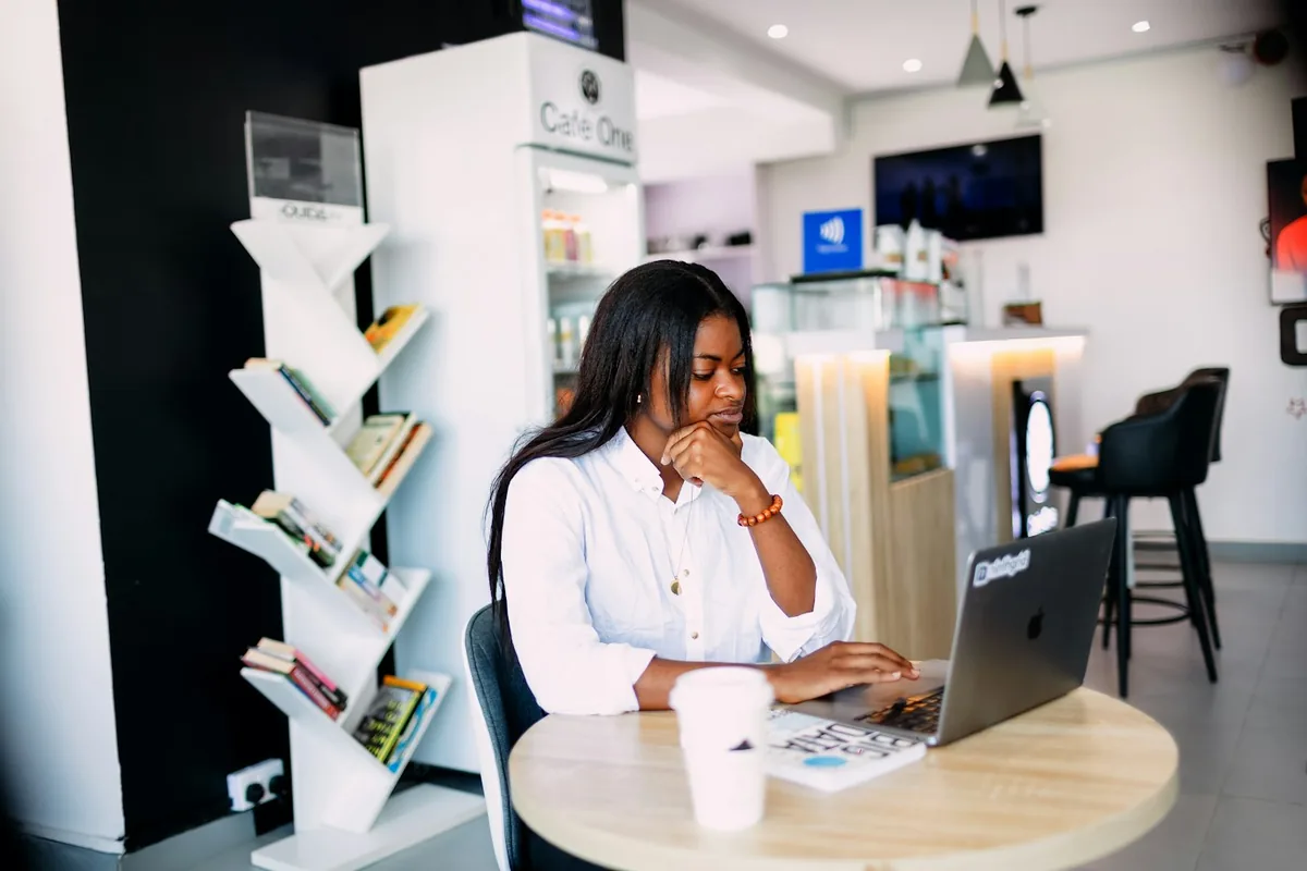 Een vrouw die op een laptop werkt aan een ronde tafel in een licht café