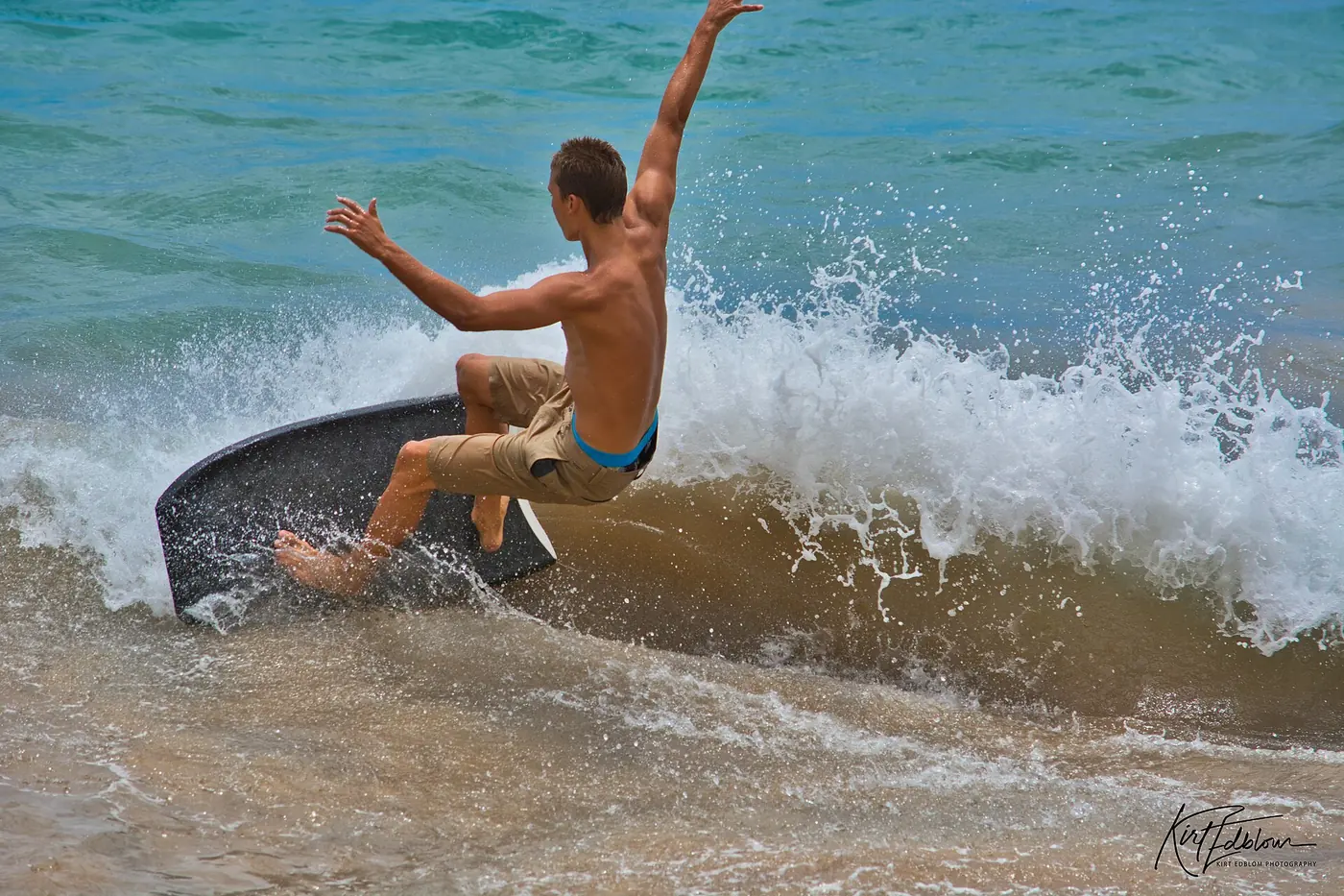 Young bodyboarder tumbling off a wave in the shallow shore break